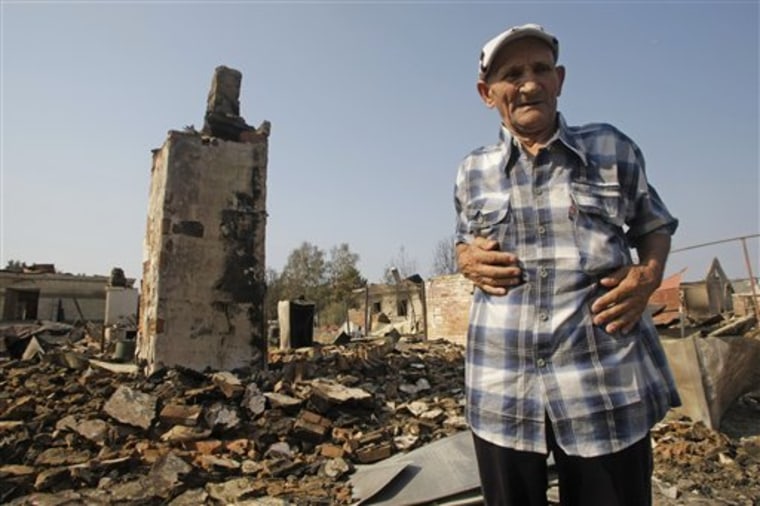 Anatoly Simaletov, 72, stands at the courtyard of his house after it was destroyed by a forest fire in the village Shuberskoe, Russia on Monday. At least 34 people have died in wildfires that have destroyed hundreds of homes and burned through vast spans of tinder-dry land.